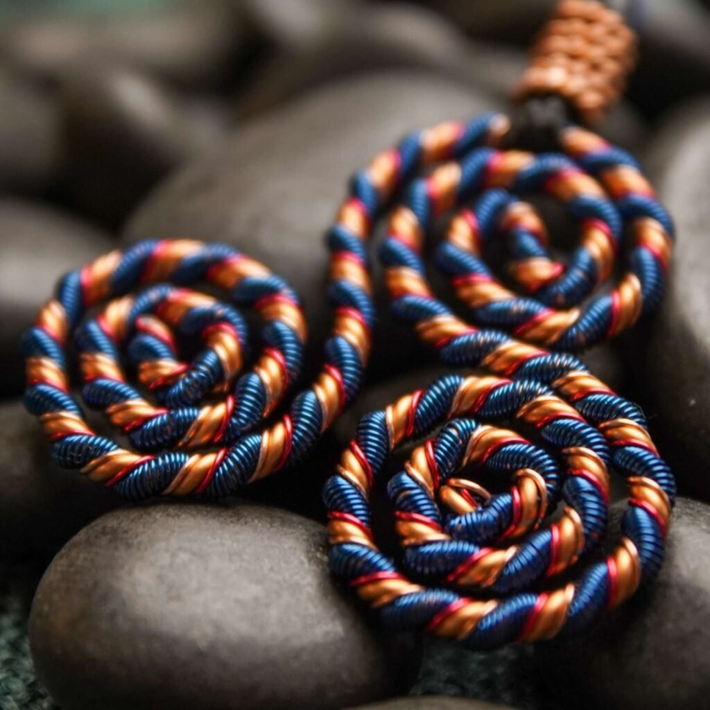 Copper energy necklace with blue and red enamel triskelion design for throat and heart chakra alignment